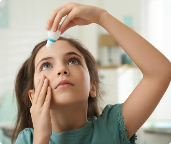 Girl applying atropine eye drops on her eyes